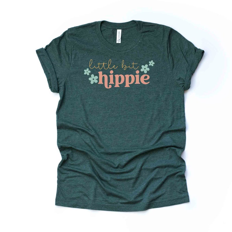 Peut inclure: Un t-shirt vert fonc&eacute; avec le texte "little bit hippie" en lettres roses et jaunes avec des accents de fleurs vertes.