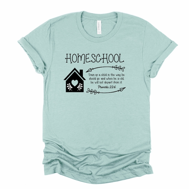 Puede incluir: Una camiseta azul claro con el texto "HOMESCHOOL" en negro. La camiseta tambi&eacute;n presenta una casa negra con un coraz&oacute;n, flores y flechas. El texto "Train up a child in the way he should go and when he is old, he will not depart from it. Proverbs 22:6" tambi&eacute;n est&aacute; impreso en negro.