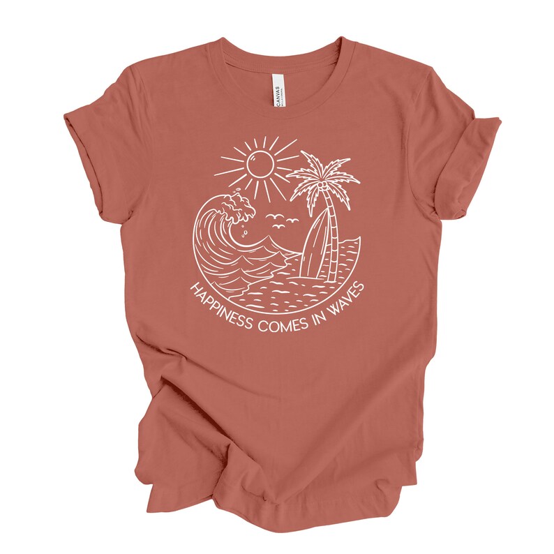 May include: A rust-colored t-shirt with a white graphic design of a sun, palm tree, surfboard, and wave. The text "Happiness comes in waves" is written below the graphic.
