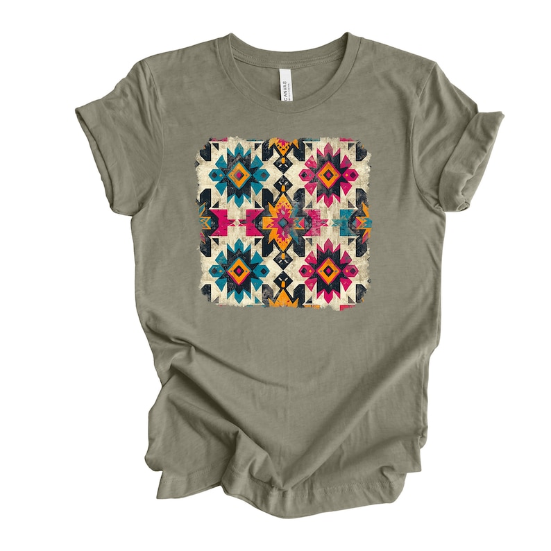 Pu&ograve; includere: Una t-shirt verde salvia con un motivo geometrico colorato stampato sul davanti. Il motivo presenta una variet&agrave; di forme e colori, tra cui rosso, blu, giallo e nero.