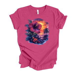 May include: A magenta t-shirt featuring a tropical design. The graphic includes a large purple hibiscus flower, palm trees, and a sunset scene. The shirt is made of a soft material and has a classic crew neck.