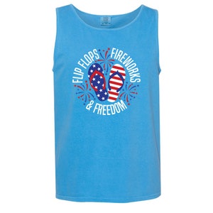 May include: A light blue tank top with a white graphic design featuring red, white, and blue flip flops and fireworks with the text "Flip Flops, Fireworks & Freedom".