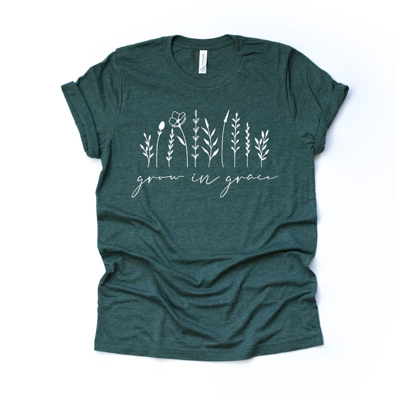 May include: A dark green t-shirt with a white graphic of stylized flowers and the text "grow in grace".