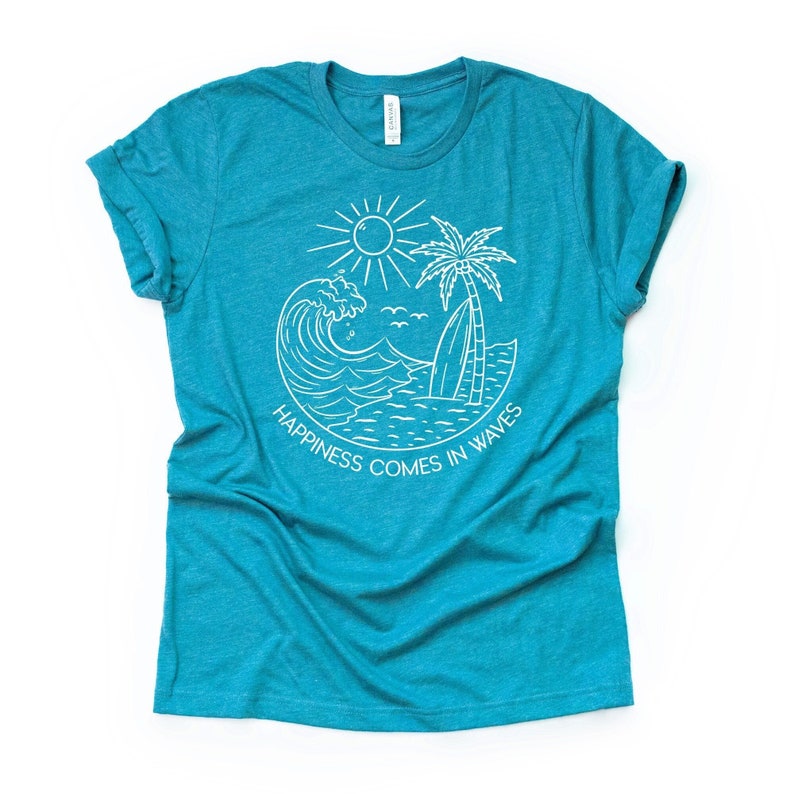May include: Teal blue t-shirt with a white graphic design of a wave, palm tree, sun, and surfboard. The text "Happiness comes in waves" is written below the graphic.
