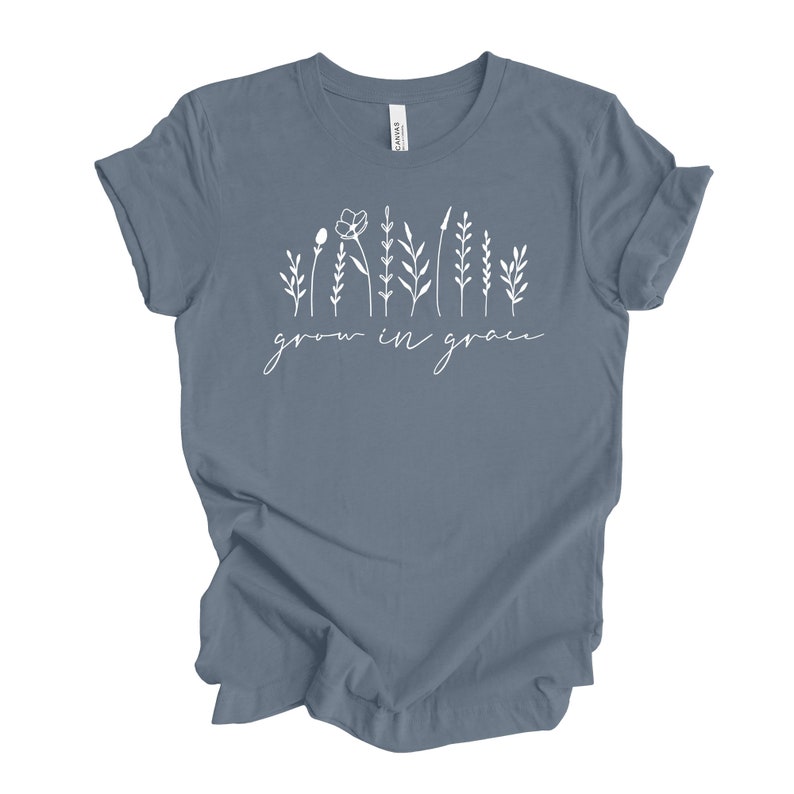 May include: A light blue t-shirt with a white graphic of stylized flowers and the text "grow in grace".