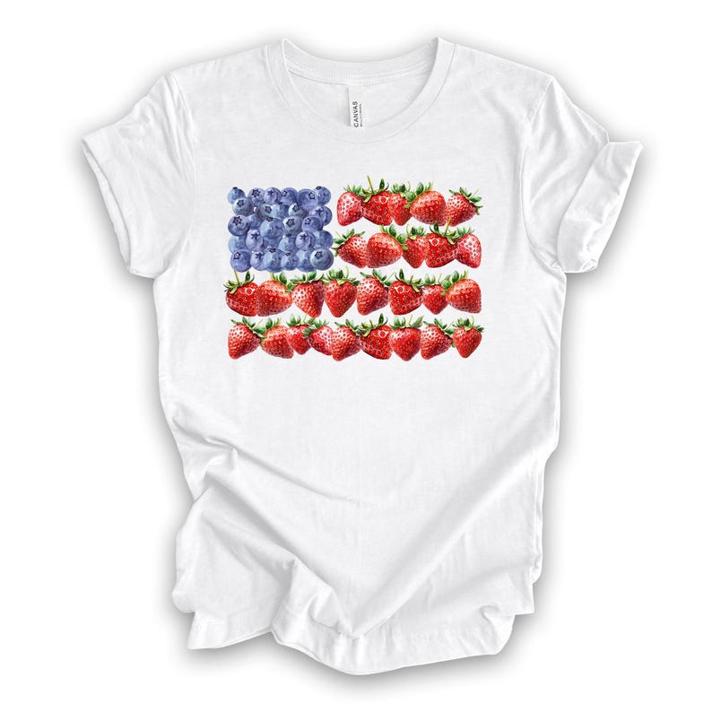 May include: White t-shirt featuring a design of the American flag made of blueberries and strawberries. The flag design is centered on the front of the shirt. The shirt is made of a soft, lightweight material.