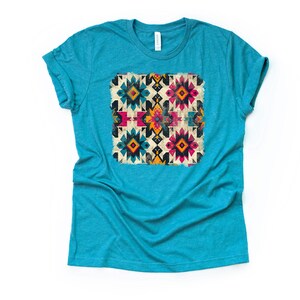 Pu&ograve; includere: Una t-shirt blu turchese con un motivo geometrico colorato stampato sul davanti. Il motivo presenta una variet&agrave; di colori, tra cui rosso, giallo, blu e nero.
