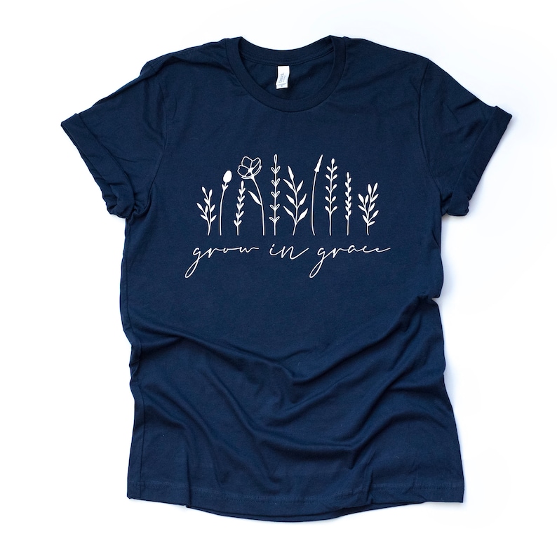 May include: Navy blue t-shirt with a white graphic of stylized flowers and the text "grow in grace".