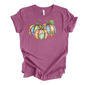 Pu&ograve; includere: Una maglietta color malva con un design di zucche colorate. Le zucche sono decorate con vari motivi, tra cui pois, cuori, strisce e quadretti. Il design &egrave; in stile acquerello, perfetto per l'autunno.