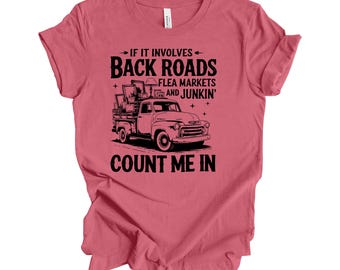 May include: A pink t-shirt with a black graphic of a pickup truck loaded with furniture and the text "→ IF IT INVOLVES - BACK ROADS FLEA MARKETS AND JUNKIN' COUNT ME IN"