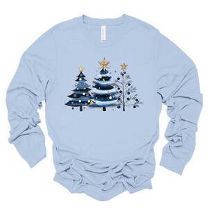 May include: A light blue long-sleeved t-shirt with a design of three stylized Christmas trees in shades of blue and gold.