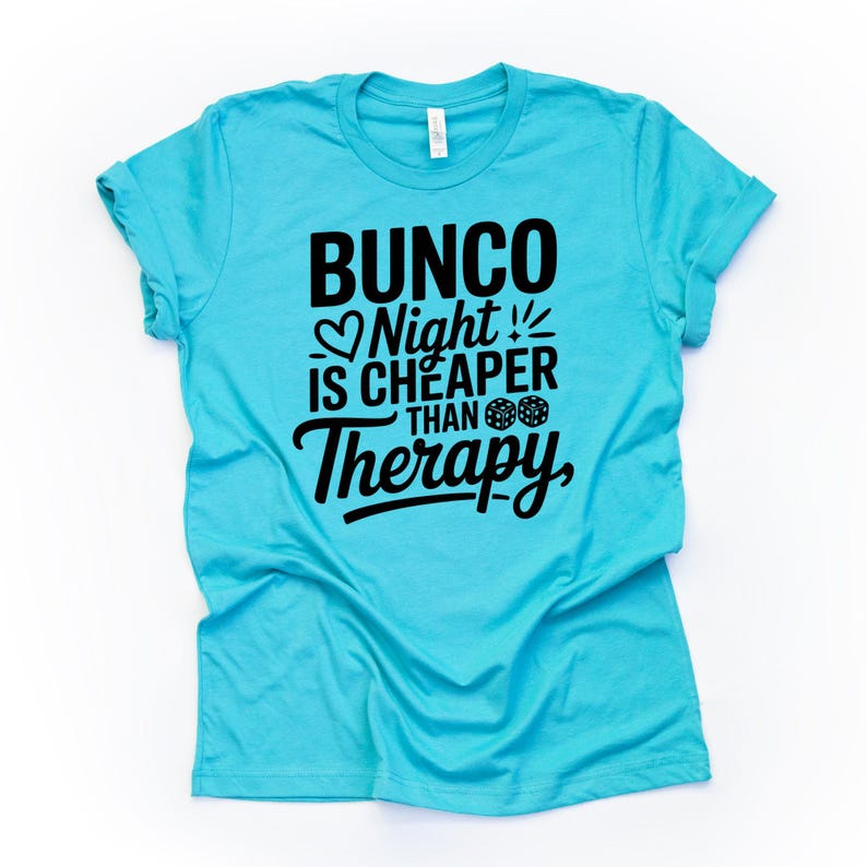 K&ouml;nnte beinhalten: Ein t&uuml;rkisfarbenes T-Shirt mit dem schwarzen Text "Bunco Night is Cheaper Than Therapy". Das Design beinhaltet ein Herz, W&uuml;rfel und Ausrufezeichen. Das T-Shirt besteht aus weichem Material und hat kurze &Auml;rmel.