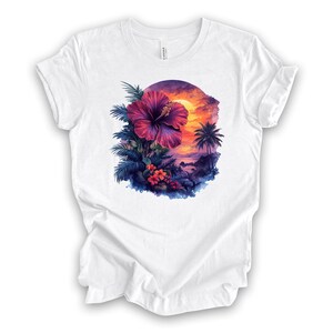 May include: White t-shirt featuring a vibrant tropical design. A large, purple hibiscus flower is the focal point, surrounded by lush green and blue foliage. The background depicts a sunset over a beach with palm trees, creating a colorful and scenic graphic.