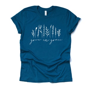 May include: Teal blue t-shirt with a white graphic of stylized flowers and the text "grow in grace".