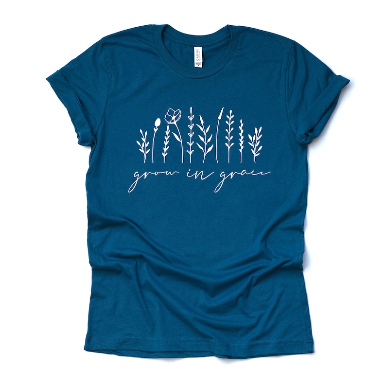 May include: Teal blue t-shirt with a white graphic of stylized flowers and the text "grow in grace".