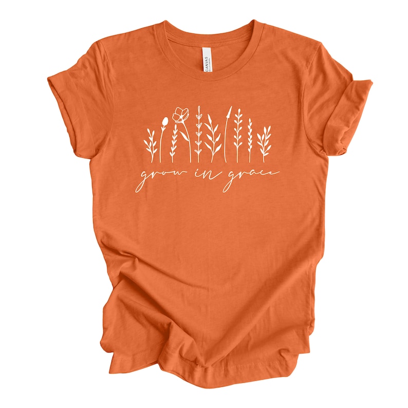 May include: Orange t-shirt with a white graphic of stylized flowers and the text "grow in grace".