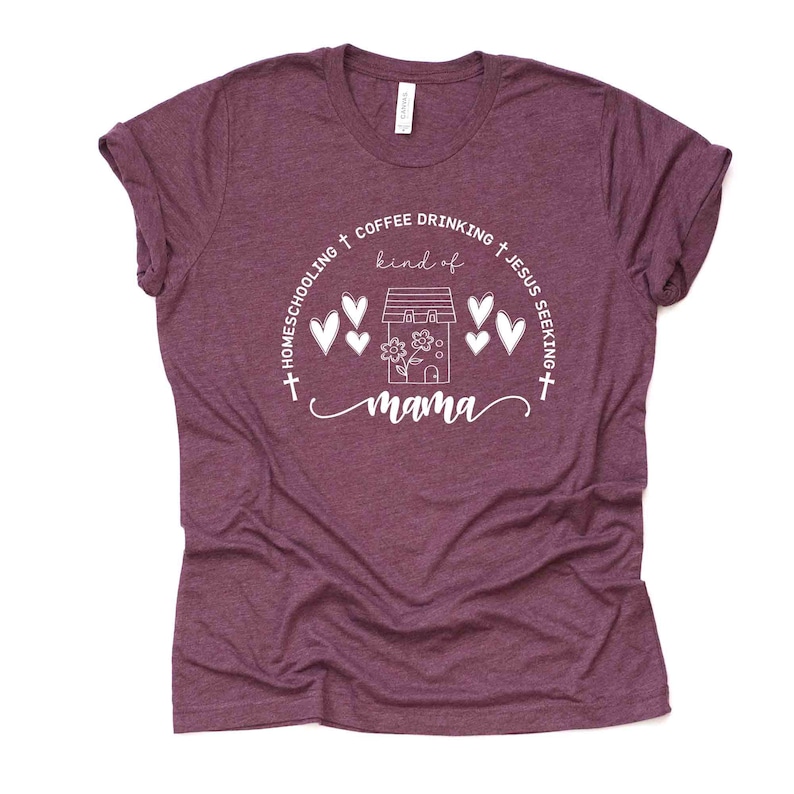 Puede incluir: Una camiseta color granate con un dise&ntilde;o gr&aacute;fico blanco que dice "Homeschooling + Coffee Drinking + Jesus Seeking + kind of mama". El gr&aacute;fico tambi&eacute;n incluye una casa con una flor y corazones.
