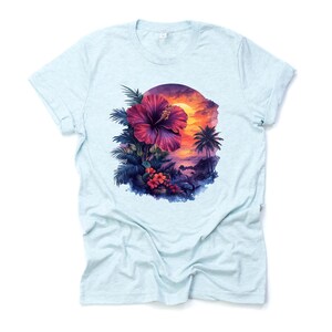 May include: Light blue t-shirt featuring a vibrant tropical design. The graphic showcases a large, deep pink hibiscus flower surrounded by lush green foliage, with a sunset scene and palm trees in the background. The design is centered on the shirt.