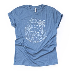 May include: A blue t-shirt with a white graphic design of a wave, palm tree, sun, and surfboard. The text "Happiness comes in waves" is written in a circle around the graphic.