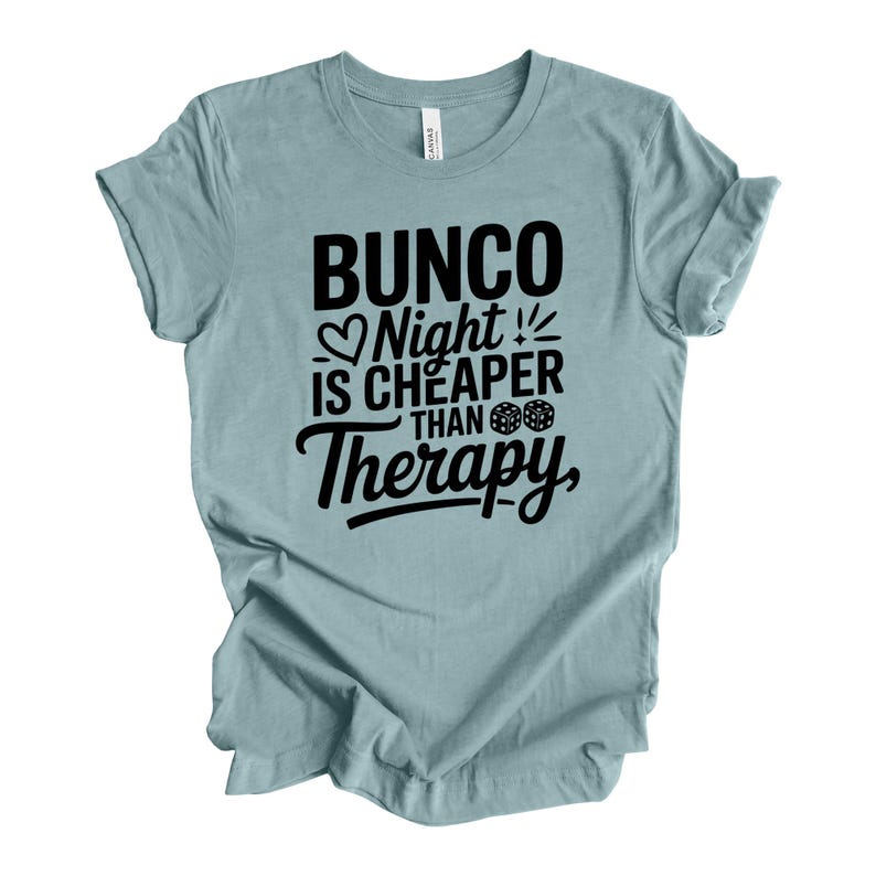 K&ouml;nnte beinhalten: Hellblaues T-Shirt mit dem schwarzen Text "Bunco Night is Cheaper Than Therapy". Der Text enth&auml;lt ein Herz, W&uuml;rfel und Ausrufezeichen. Das T-Shirt ist aus weichem Stoff.