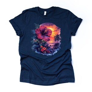 May include: Navy blue t-shirt featuring a vibrant tropical scene. A large, deep red hibiscus flower is the focal point, surrounded by lush green foliage and smaller red flowers. The background depicts a sunset over a tropical landscape with palm trees.