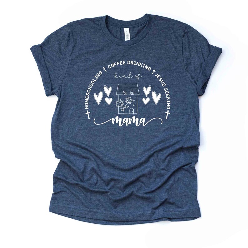 Puede incluir: Una camiseta azul marino con un dise&ntilde;o gr&aacute;fico blanco que dice "Homeschooling + Coffee Drinking + Jesus Seeking + kind of mama" con una casa y corazones alrededor.