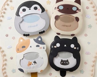 Puede incluir: Cuatro marcos de fotos caprichosos con forma de animales de dibujos animados. Los marcos representan un pingüino, un gato siamés, un gato calicó y un gato negro. Cada marco tiene una abertura central para una foto y está decorado con bonitos detalles.
