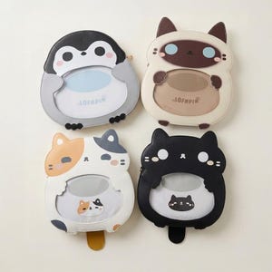 Könnte beinhalten: Vier charakterförmige Taschen mit durchsichtigen Sichtfenstern. Oben links ein grauer und weißer Pinguin. Oben rechts eine cremefarbene und braune Katze. Unten links eine weiß-orange-graue Glückskatze. Unten rechts eine schwarze Katze. Jede Tasche trägt den Schriftzug LOFNPIN.