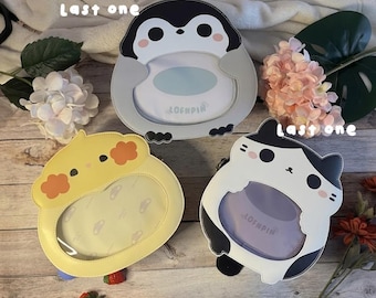 May include: Three animal-shaped purses: a penguin, a cat, and a bird. The penguin purse is gray and white, the cat purse is black and white, and the bird purse is yellow and orange. Each purse has a clear window and the text "LAST ONE".