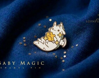 May include: A cream-colored enamel pin featuring a small creature with long ears holding a yellow star-shaped object, surrounded by small gold star accents. The text BABY MAGIC ENAMEL PIN and the brand name LOFNPIN are visible in the image.