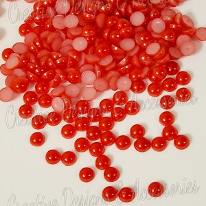 May include: A large pile of red and pink round cabochons. The cabochons are smooth and shiny.