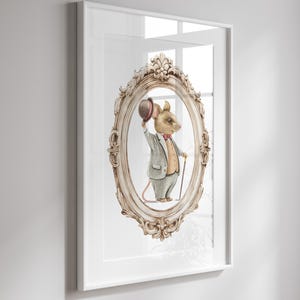 May include: A framed print featuring a watercolor illustration of a mouse dressed in a suit, holding a bowler hat. The mouse is inside an ornate, oval-shaped frame. The frame is set against a white background.
