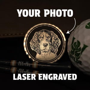 May include: A laser-engraved golf ball marker with a dog portrait. The round marker has a gold-coloured rim and a black centre. The text "YOUR PHOTO" and "LASER ENGRAVED" are displayed in white.