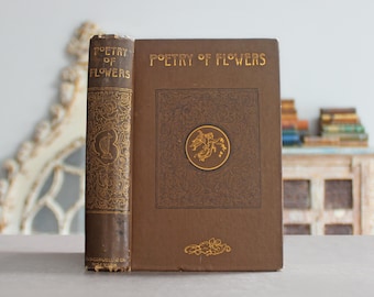 May include: A vintage book titled "Poetry of Flowers" with a brown cover and gold lettering. The book's spine is visible, featuring ornate gold detailing and the title. A gold emblem is centered on the front cover. The book is a classic piece of literature.