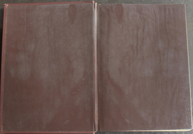 May include: An open book with a dark brown cover. The pages are visible, and the book is lying flat. The cover has a slightly textured appearance, with a darker shade of brown along the edges.