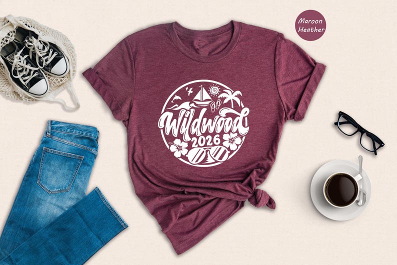 a casual outfit consisting of a burgundy t-shirt with a graphic design, a pair of blue jeans, a pair of black sneakers, a pair of glasses, a white coffee cup, and a straw hat.
