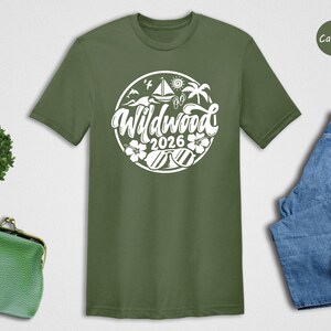 a green t-shirt with a white graphic design, a pair of blue jeans, a pair of white sneakers, a green purse, and a small green plant.