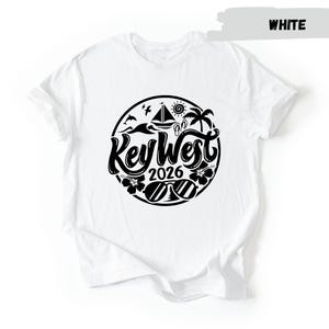 A white t-shirt with a black graphic design featuring the text "Key West 2016" surrounded by various icons and symbols associated with the location.