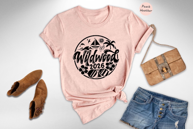 A pink t-shirt with a graphic design, a pair of brown ankle boots, a beige handbag, and a pair of denim shorts are arranged on a white background.