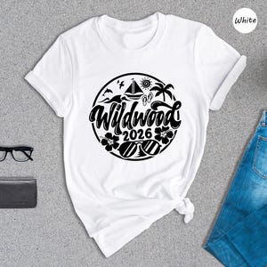 a white t-shirt with a graphic design, a pair of blue jeans, a pair of glasses, a wallet, and a potted plant, all laid out on a gray surface.