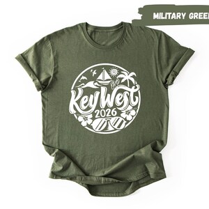 A green t-shirt with a white graphic design featuring a circular emblem with text and illustrations related to the year "2016" and the word "Key West".