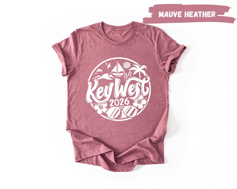 A maroon t-shirt with a white graphic design featuring the text "Key West" and "2016" surrounded by various beach and ocean-themed illustrations.