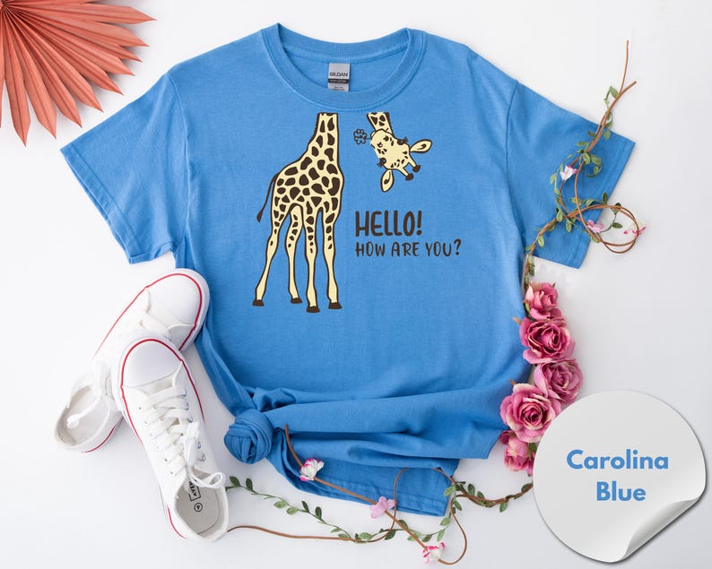 A blue t-shirt with a giraffe and the text "HELLO HOW ARE YOU?" printed on it, along with a pair of white sneakers and pink flowers.