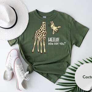 a green t-shirt with a giraffe and a smaller giraffe, along with a hat, sneakers, and a palm leaf.