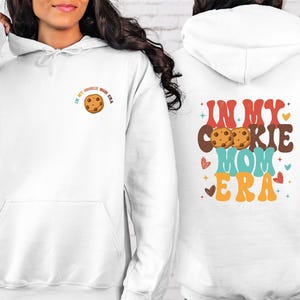 a woman wearing a white hoodie with a cookie on it