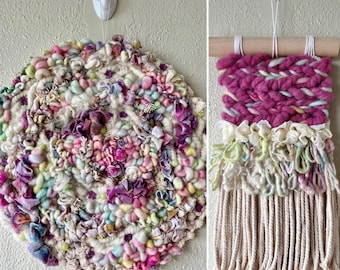 May include: Two colorful wall hangings made with yarn and fabric. The first is a round, circular piece with a swirling pattern of pink, purple, white, and green yarn. The second is a rectangular piece with a pink and white woven pattern and a fringe of white yarn.