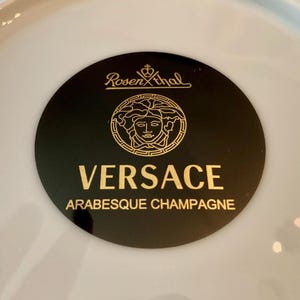 May include: A black and gold Versace Arabesque Champagne plate with the Rosenthal logo.