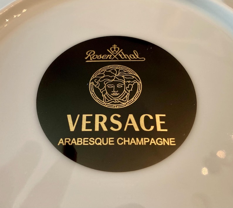 May include: A black and gold Versace Arabesque Champagne plate with the Rosenthal logo.