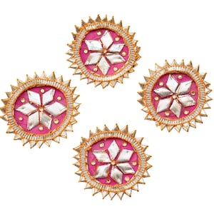 May include: Four pink and gold decorative round ornaments with a silver star design in the center.