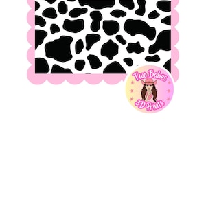 May include: A rectangular graphic with a black and white cow print pattern, framed by a scalloped light pink border. A circular logo in the bottom right corner features a cartoon character in a pink cowboy hat with the text Two Babes 3D Prints.